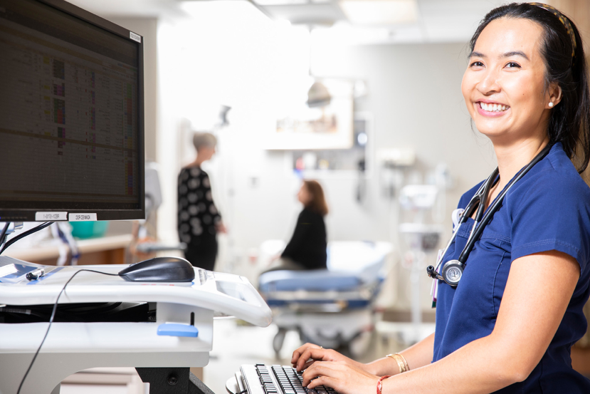 female doctor smiling and typing on computer